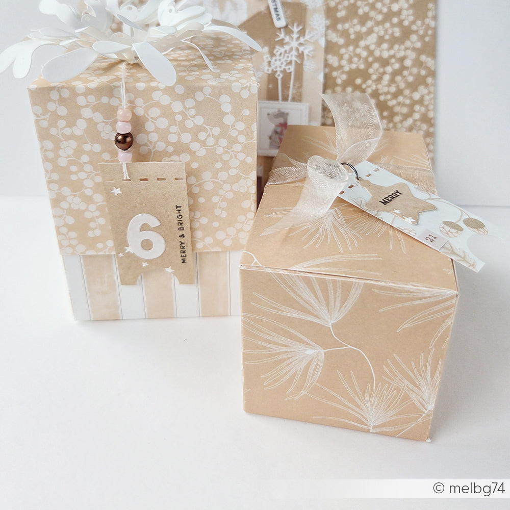 Zwei Geschenke, verpackt in Designpapier mit botanischen Mustern, Bändern und nummerierten Anhängern.