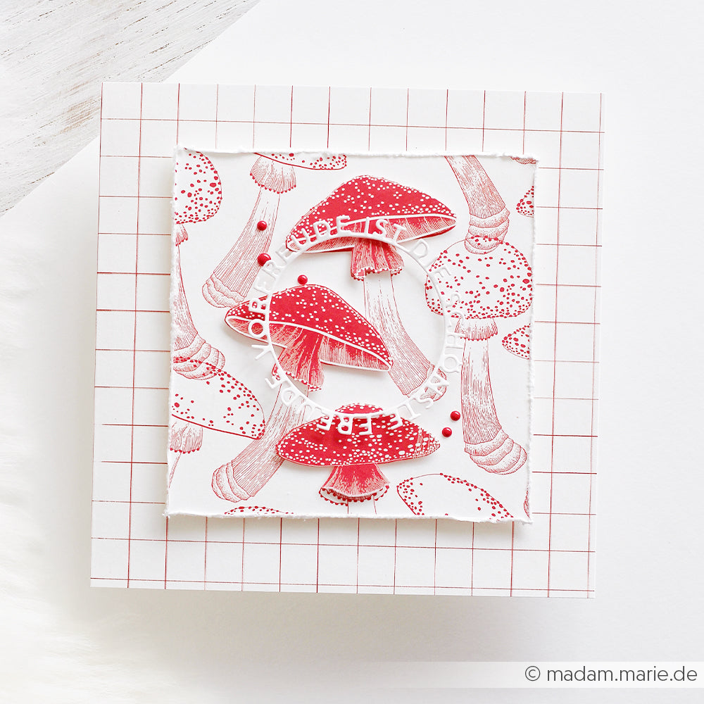 Handgefertigte Grußkarte mit einem rot-weißen Pilz-Motiv aus Designpapier und einem kreisförmigen Schriftzug.