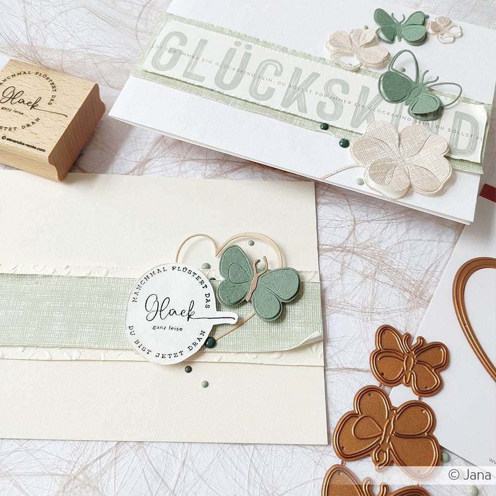 Handgefertigte Karten von Alexandra Renke mit Schmetterlingsdetails, Buchbinderei, Designpapier Leinen Pastellgrün, deutschem Text, Stempeln und Metallschmetterlingsstanzen - perfekt für Papierprojekte.