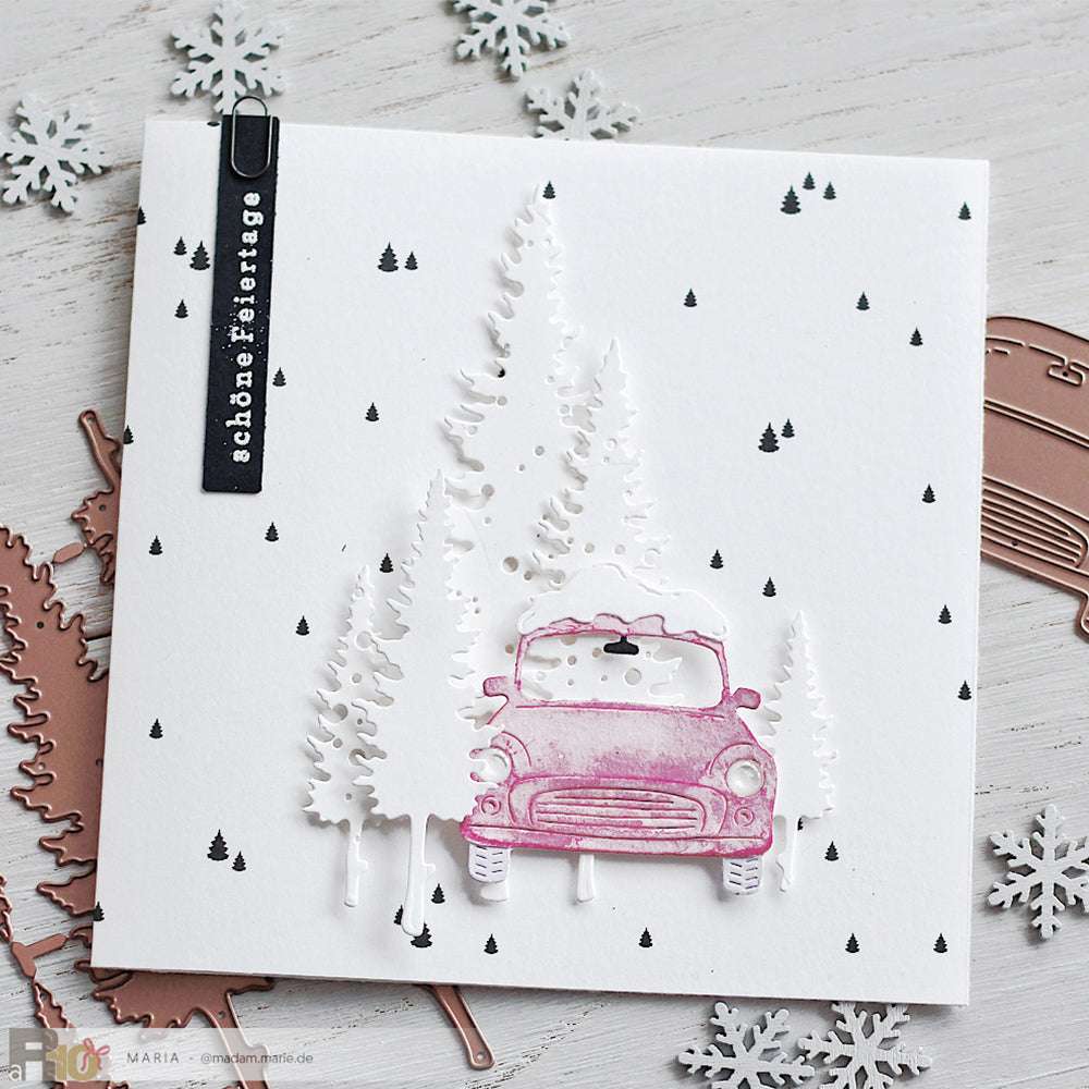 Handgemachte Weihnachtskarte von Alexandra Renke mit einem rosa Auto, weißen Bäumen, die mit dem Fünf Tannen Set Motivstanze geschnitten wurden, einem schwarzen Weihnachtsgruß und verstreuten schwarzen Punkten und Dreiecken auf hochwertigem Designpapier.