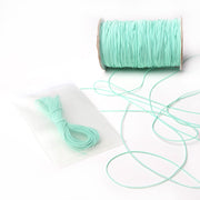 Eine Spule hellblaues Alexandra Renke Elastikband mit einem losen Bündel, ideal für jedes Bastelprojekt, kommt in einem wiederverschließbaren Beutel auf weißem Hintergrund.