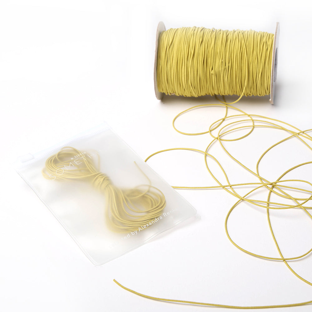 Eine Spule gelber Schnur von Alexandra Renke, ideal für jedes Bastelprojekt oder in Kombination mit Elastikband für kreative Bastelarbeiten.