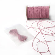 Eine Spule rosa Alexandra Renke Elastikband mit einem kleinen Bündel und loser Schnur in einem durchsichtigen Beutel - ideal für Ihr nächstes Bastelprojekt.