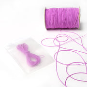 Eine Spule rosa Elastikband von Alexandra Renke mit einem passenden Bündel in einem durchsichtigen Beutel - ideal für Ihr nächstes Bastelprojekt - präsentiert auf einer weißen Fläche.