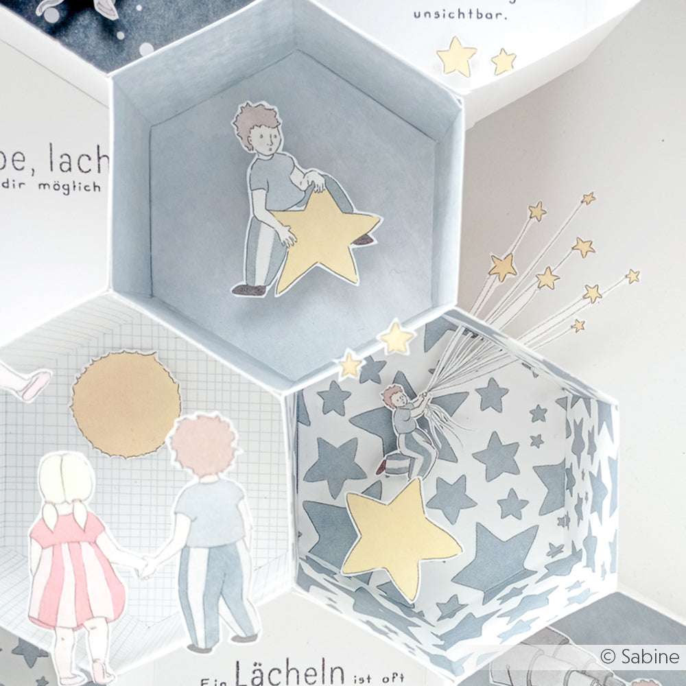 Illustrierte Kinder halten Sterne in Alexandra Renkes Hexagonbox-Kreationen, die mit Sternenmustern und sanften Pastellfarben auf hochwertigem Designpapier aufwarten.