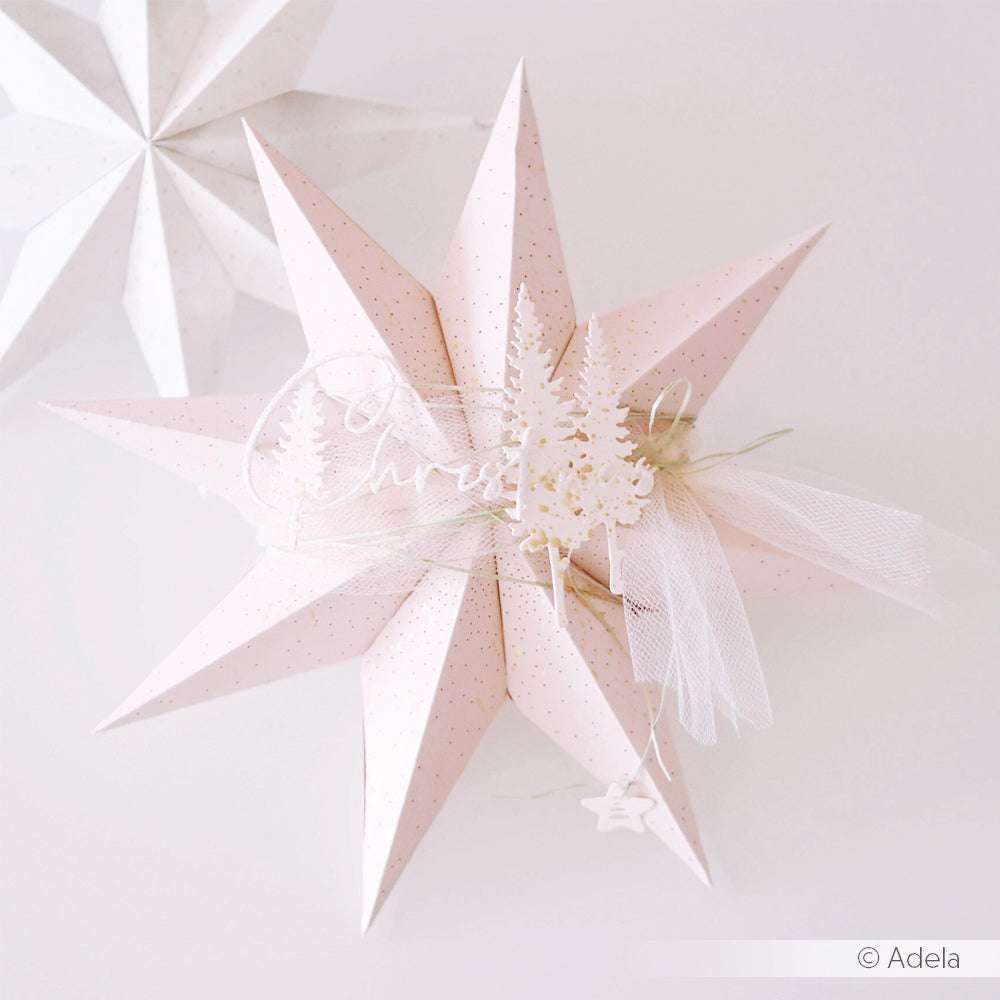 Ein blassrosa 3D-Papier-Faltstern-Ornament von Alexandra Renke mit weißen Bäumen, Tüll und weihnachtlichen Schriftzügen, hergestellt mit der Motivstanze für präzise Details.