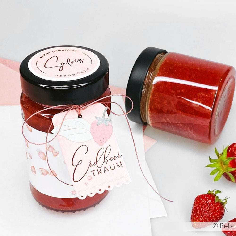 Zwei Gläser mit Erdbeermarmelade - eines aufrecht stehend mit einem dekorativen Alexandra Renke Erdbeertraum-Etikett, das andere liegend - sowie Erdbeeren eignen sich perfekt für die Gestaltung süßer Motive mit Ihrem Alexandra Renke Clear Stamp Set oder Photopolymer Stempel.