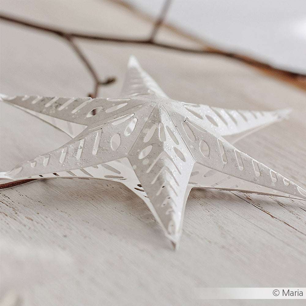 Weißes Papierstern-Ornament mit ausgeschnittenen Mustern, hergestellt mit Alexandra Renke Motivstanze Steckstern und DieCut Systemen, ausgestellt auf einer hellen Holzoberfläche.