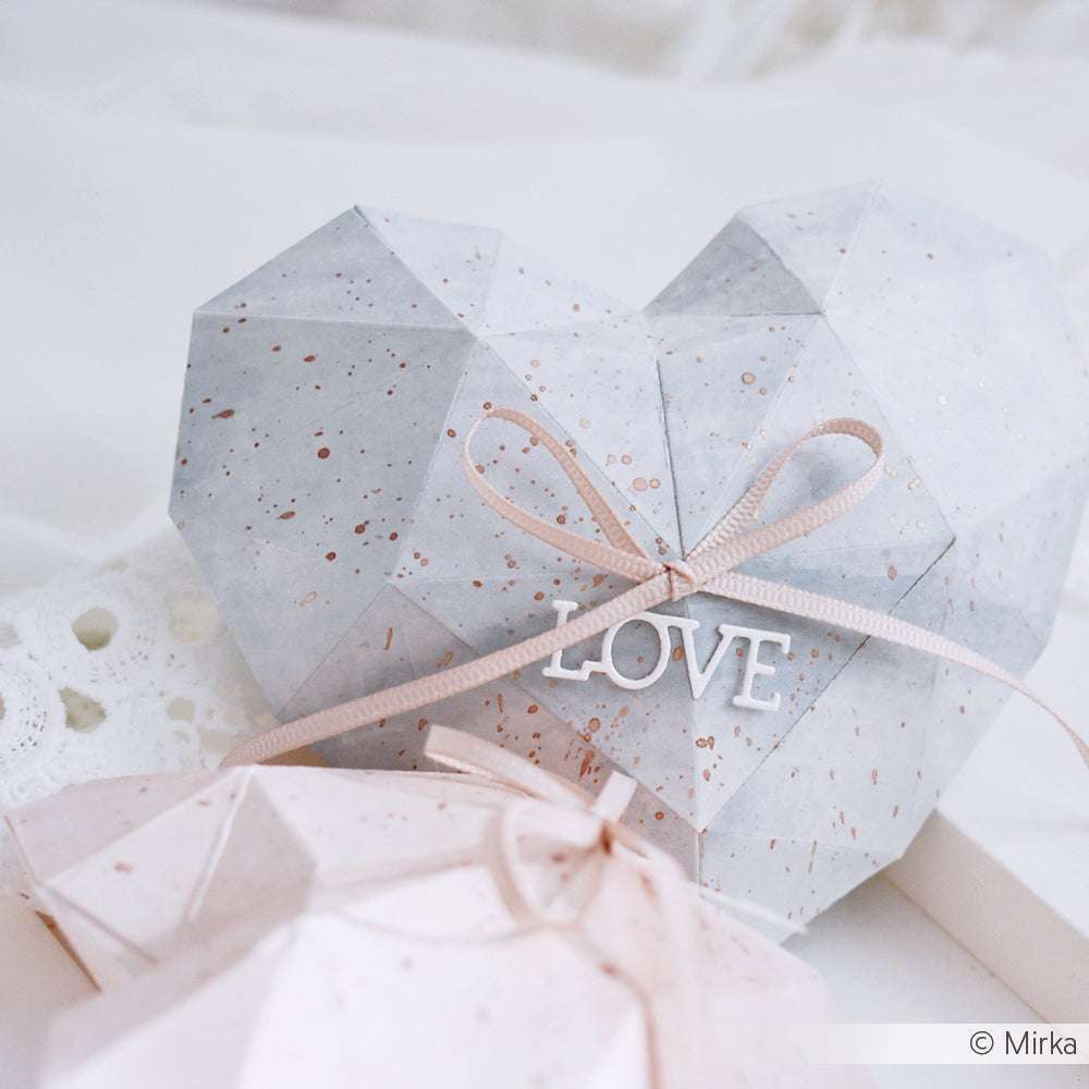 Geometrischer Geschenkkarton in Herzform, gestaltet mit Alexandra Renke Designpapieren und veredelt mit der Großen 3D Herz Motivstanze, verziert mit einer rosa Schleife und einem LOVE Anhänger auf weißem Spitzenhintergrund.