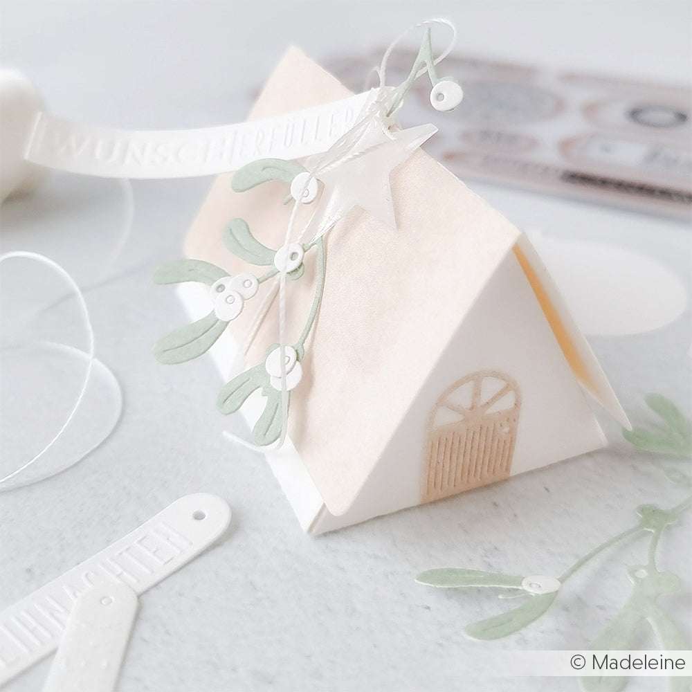 Kleines weißes Papierhaus von Alexandra Renke, verziert mit grünem Mistelzweig, Stern und WUNSCHERFÜLLER-Etikett - ideal zum Basteln mit DieCut Systemen oder einer Motivstanze Dreieck Klappbox.