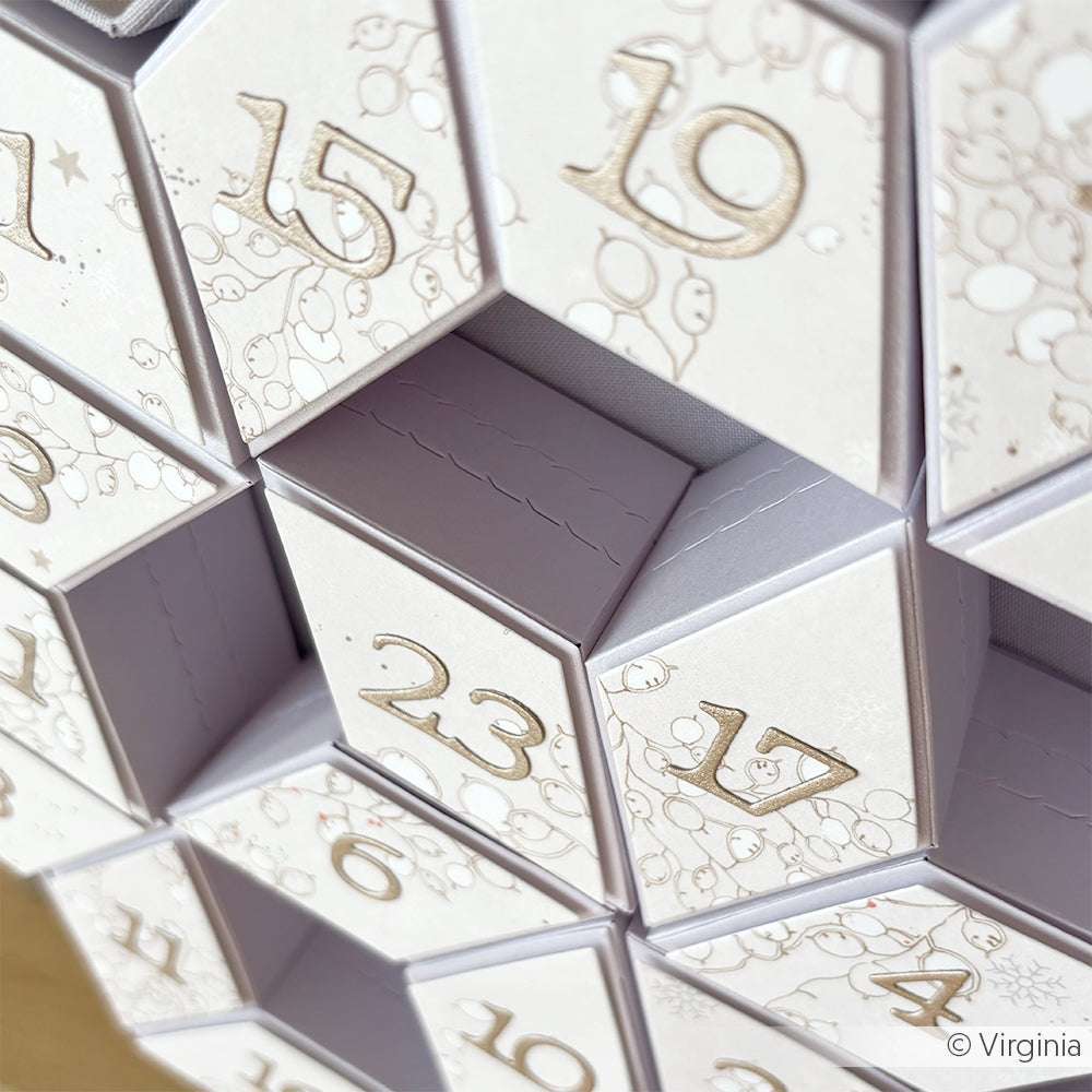 Nahaufnahme eines weißen Alexandra Renke-Adventskalenders mit nummerierten Türchen - darunter 15, 17, 19 und 23 -, der mit Stanzsystemen für präzise Details gefertigt wurde.