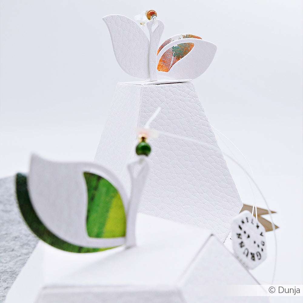 Zwei weiße, strukturierte Pyramidenschachteln, hergestellt mit Alexandra Renke Motivstanze Birnen Box, verziert mit blattförmigen Akzenten und kleinen Perlen auf der Oberseite.