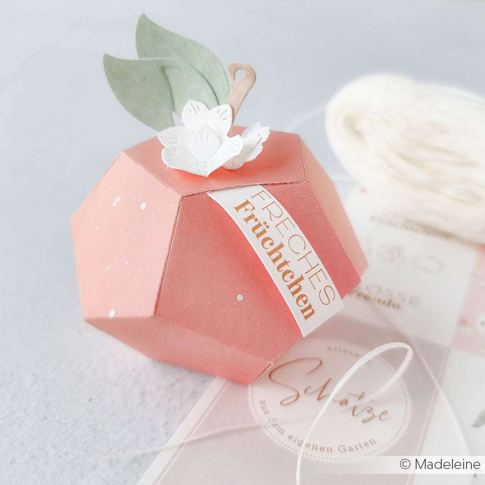 Eine pfirsichförmige Papierschachtel mit Blatt und Blüte mit der Aufschrift "Freches Früchtchen", hergestellt mit Alexandra Renke Motivstanze Apfel Box Dies.