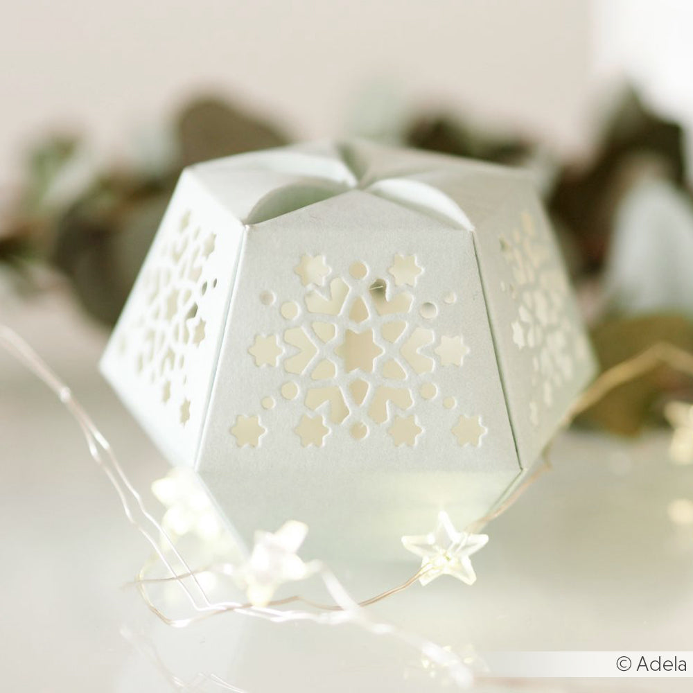 Weiße Papierlaterne von Alexandra Renke mit einem ausgeschnittenen Schneeflockenmuster aus Deep Edge Motivstanzen, umgeben von einer sternförmigen Lichterkette.