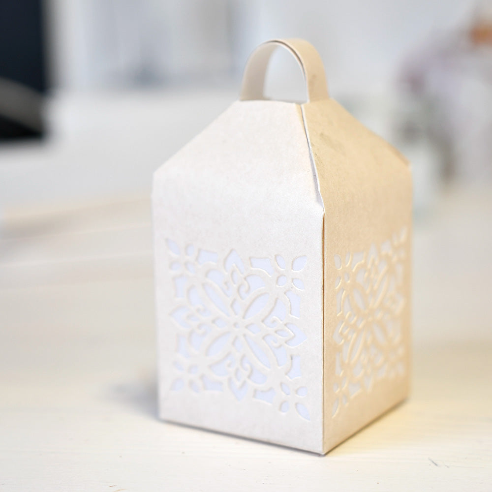 Weiße Papierlaterne mit verschlungenen Deep Edge Motivstanzen-Ausschnitten von Alexandra Renke, die auf einer hellen Fläche platziert sind - perfekt, um Ihrer Einrichtung einen einzigartigen Charme zu verleihen.