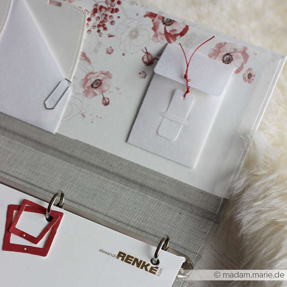 Nahaufnahme einer Mappe mit Blumenpapier, Alexandra Renke PAPPcut®ies, kleinen Umschlägen aus der Motivstanze Mini Umschlag, einer Büroklammer und quadratischen Zierklammern.
