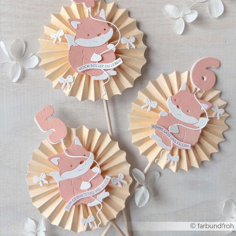 Drei Papier-Cupcake-Topper von Alexandra Renke mit niedlichen Füchsen, den Zahlen 5 und 6 und deutschen Geburtstagsgrüßen auf pastellfarbenen Rosetten, hergestellt mit Deep Edge Motivstanzen und PAPPcut®ies für eine charmante Partydekoration.