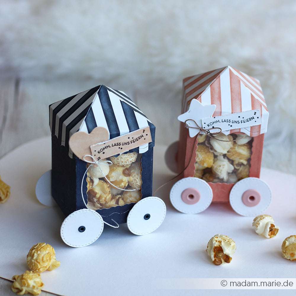 Zwei dekorative Popcornboxen in Form von Zirkuswagen mit gestreiften Aufsätzen und Papierrädern von Alexandra Renke, gestaltet mit Details der Motivstanze Festliche Zelt Box, bringen festlichen Charme auf jede Party.