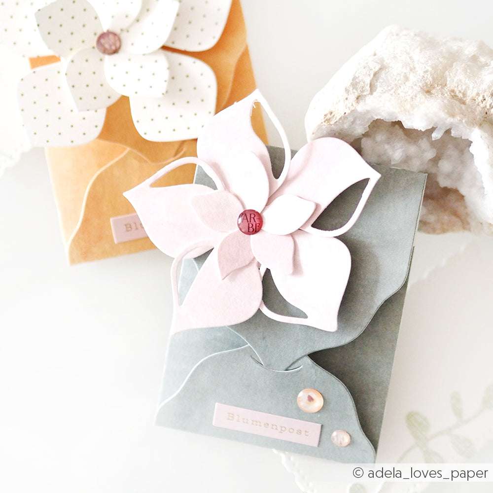 Zwei handgefertigte Karten mit großen Papierblumen aus der Alexandra Renke Motivstanze Faltzauber-Blume und verzierten Knöpfen, vor hellem Hintergrund.