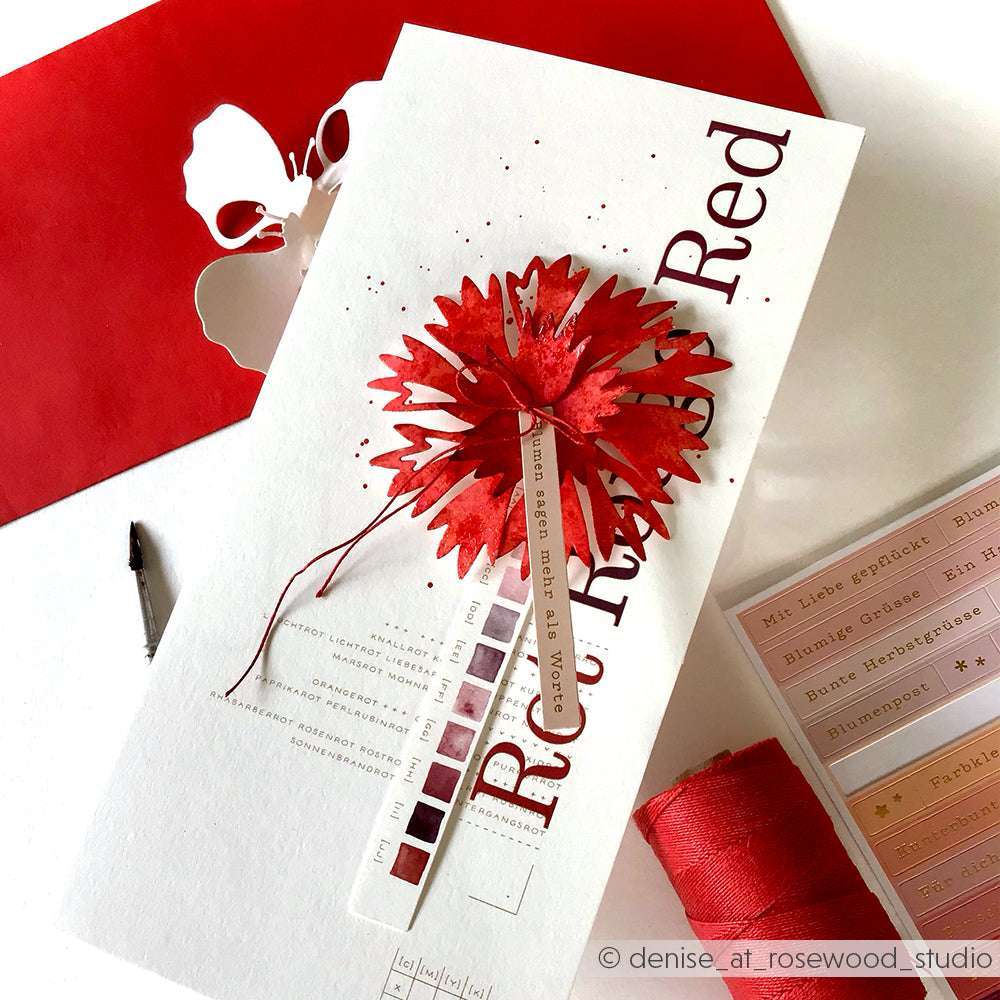 Handgefertigte Karte mit einer roten Papierblume, die mit Alexandra Renke Motivstanze Faltzauber-Kornblume und PAPPcut®ies, sowie Farbmustern und Deep Edge Motivstanzen auf weißem Untergrund gebastelt wurde.
