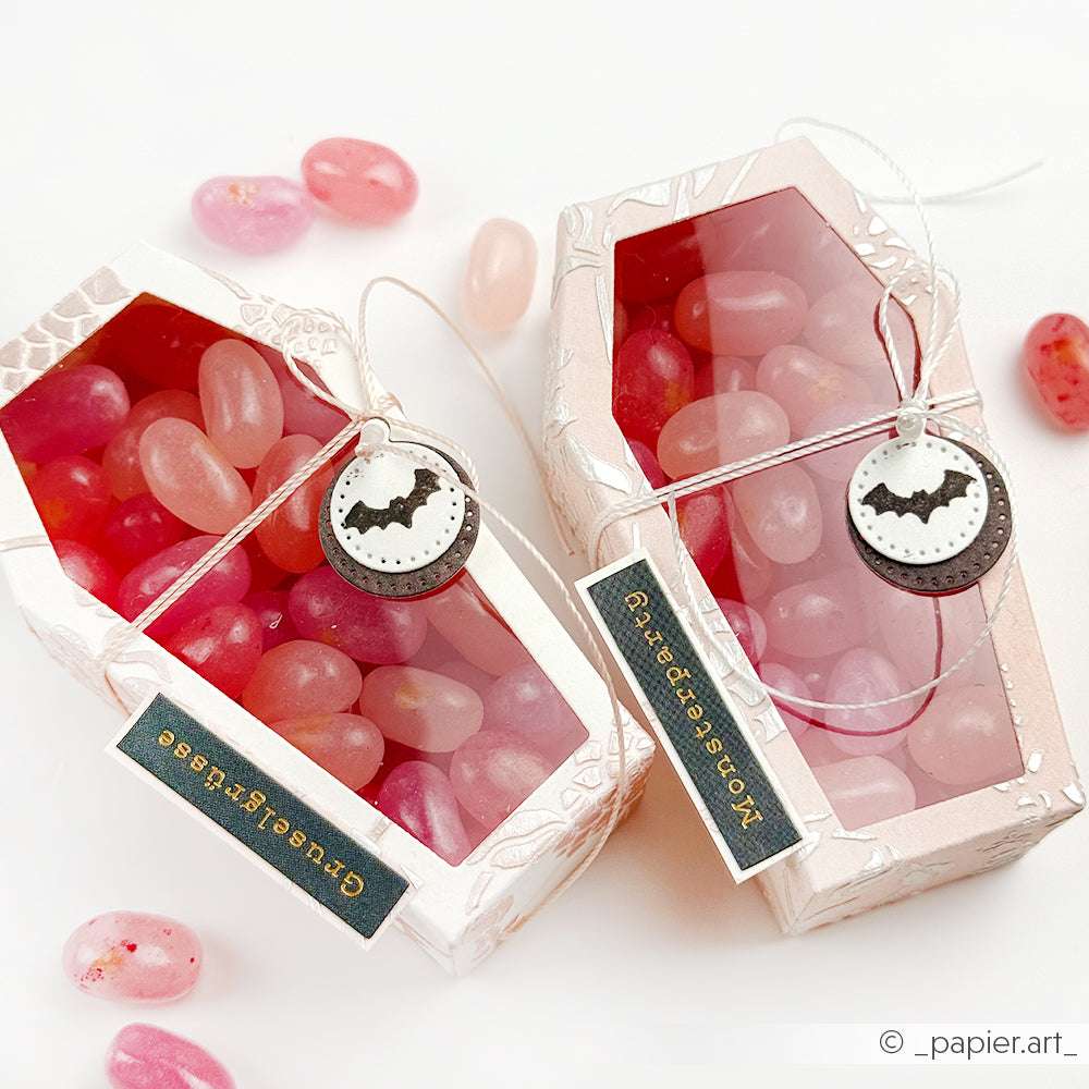 Zwei rosafarbene sargförmige Schachteln von Alexandra Renke, die mit dem Sargbox Stanzsystem hergestellt wurden, sind mit rosafarbenen Gummibärchen gefüllt und mit Fledermausanhängern und kleinen Etiketten verziert.