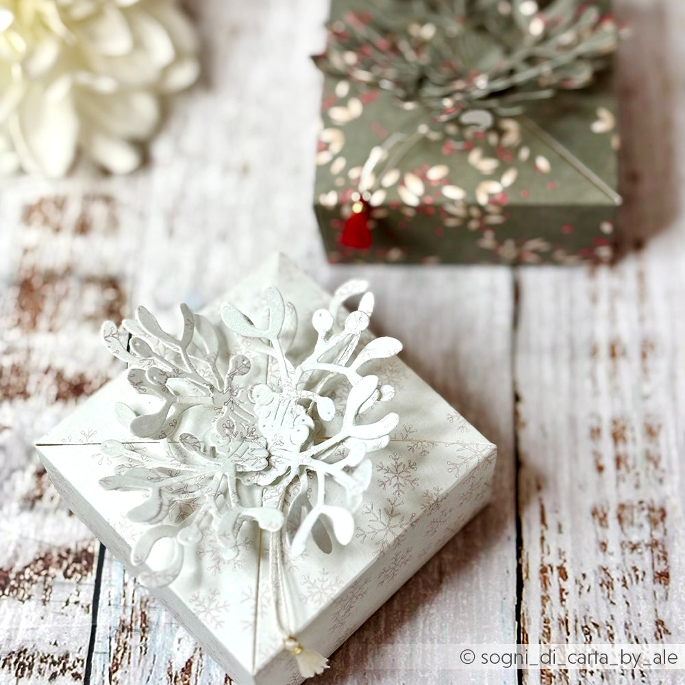 Zwei mit Alexandra Renke Stanzen für Designpapier gestaltete Geschenkboxen: eine weiße mit gestanztem Blumendetail und eine grüne mit rotem Blumenmuster.