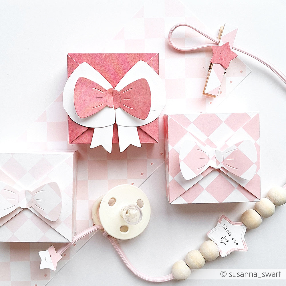 Eine rosa-weiße Geschenkbox aus Designpapier von Alexandra Renke mit eleganten Details, die mit einer Schleifenbox-Motivstanze hergestellt wurden.