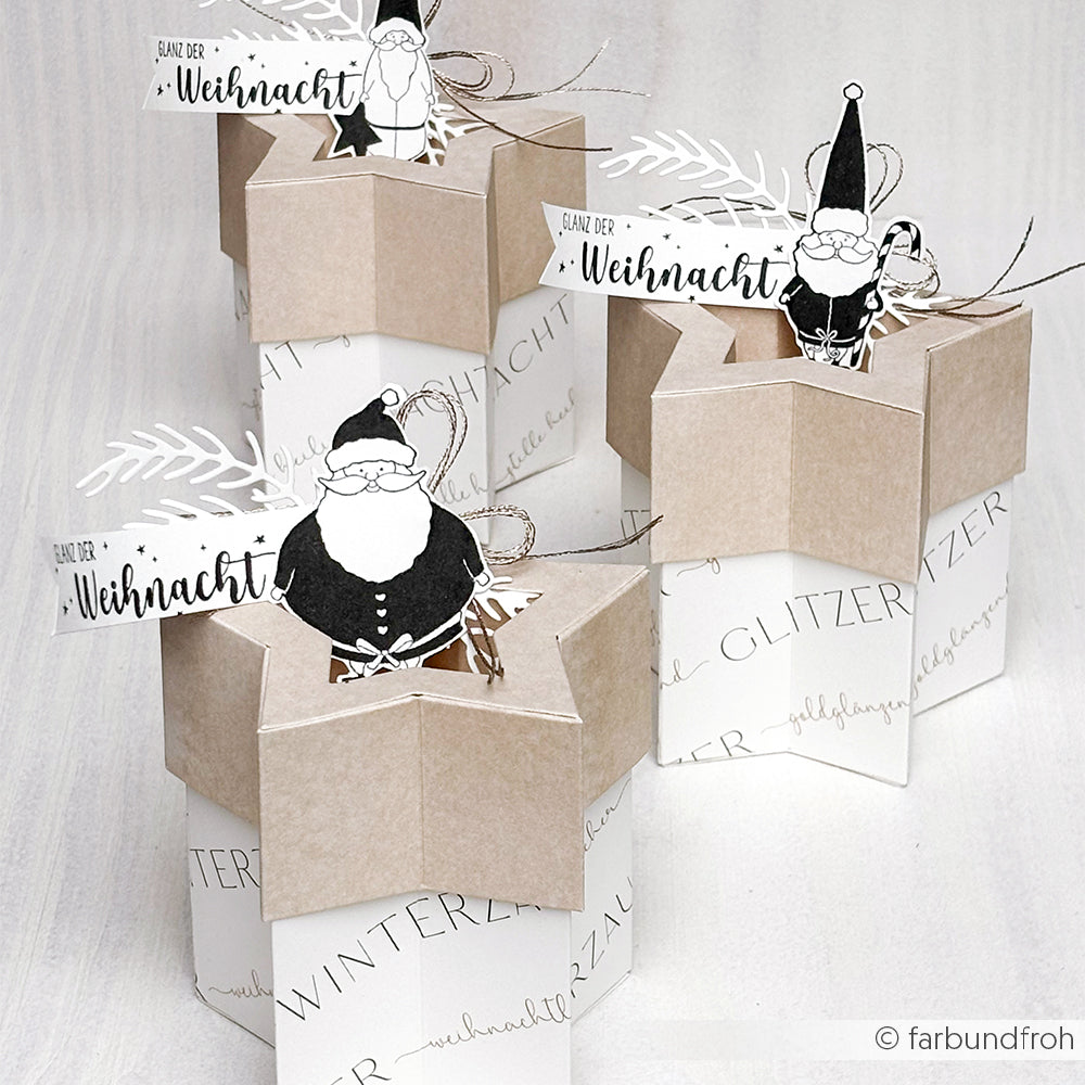 Drei sternförmige Geschenkboxen mit der Motivstanze Stern-Box von Alexandra Renke und festlicher Weihnachtsmann-Dekoration, gefertigt aus leuchtenden Designpapieren und arrangiert mit fröhlichen Anhängern auf einer hellen Fläche.