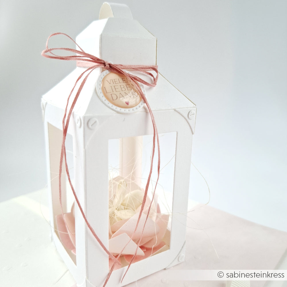Weiße Papierlaterne mit rosa Schleife, Anhänger "Viele Liebe" und gefüllt mit rosa Blütenblättern und Stroh. Hergestellt mit Alexandra Renke Designpapieren und Motivstanze Laternen Box Stanzsysteme für eine zarte handgemachte Note.