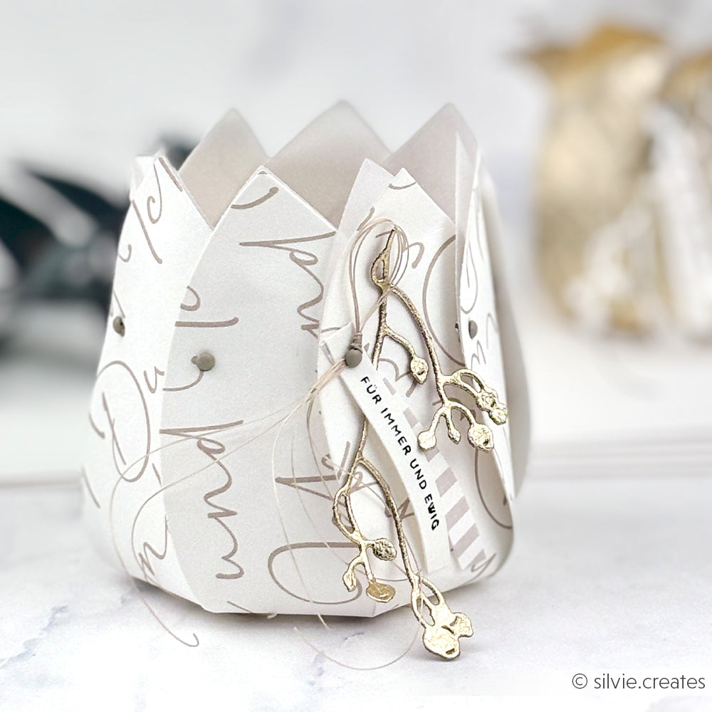 Elegante weiße Papierlaterne von Alexandra Renke, hergestellt aus Designpapier. Mit goldener Schrift, einem dezenten goldenen Zweig und einem "FÜR IMMER UND EWIG"-Anhänger - und Akzenten aus dem Motivstanze Blütenkörbchen für einen raffinierten Touch.