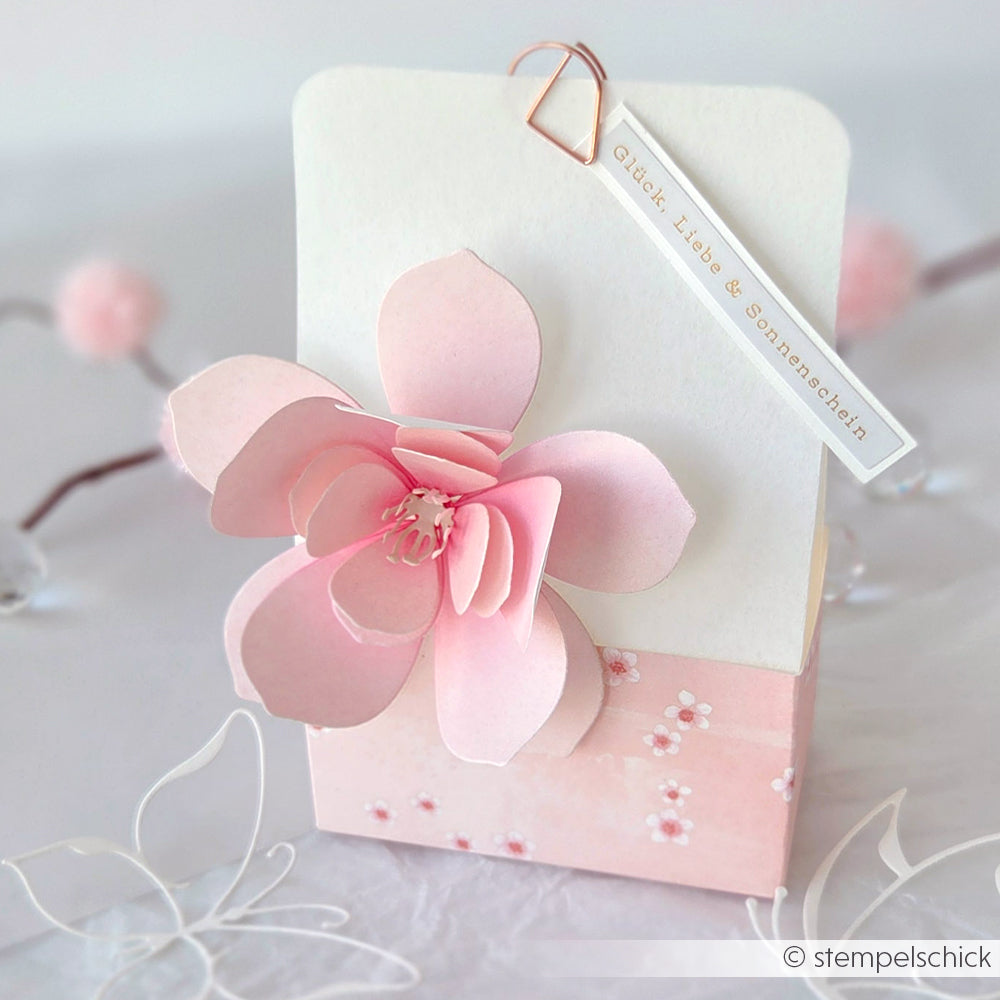 Diese rosa-weiße, handgefertigte Karte von Alexandra Renke zeigt eine 3D-Kirschblüte, feines Designpapier und ein Schild mit der Aufschrift "Glück, Liebe & Sonnenschein".