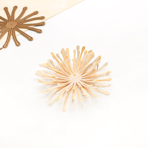Ein beiger, blumenförmiger Papierschnitt mit strahlenförmig angeordneten Blütenblättern auf weißem Hintergrund, gefertigt mit Alexandra Renke DieCut-Systemen und hochwertigen Designpapieren für präzise Details und eine elegante Optik.