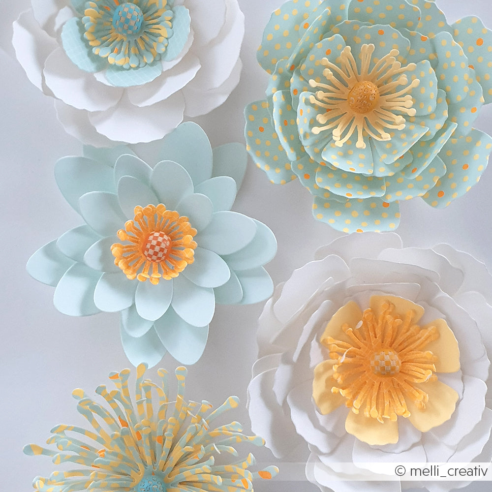 Fünf pastellfarbene Papierblumen mit gelben Blütenmitten, teilweise mit Punkten, auf weißem Hintergrund angeordnet. Diese zarten Blüten wurden mit Stanzsystemen und Stanzformen gefertigt, darunter die Motivstanze „3D Sternensee Rose“, die für zusätzliche Tiefe und Details sorgt.