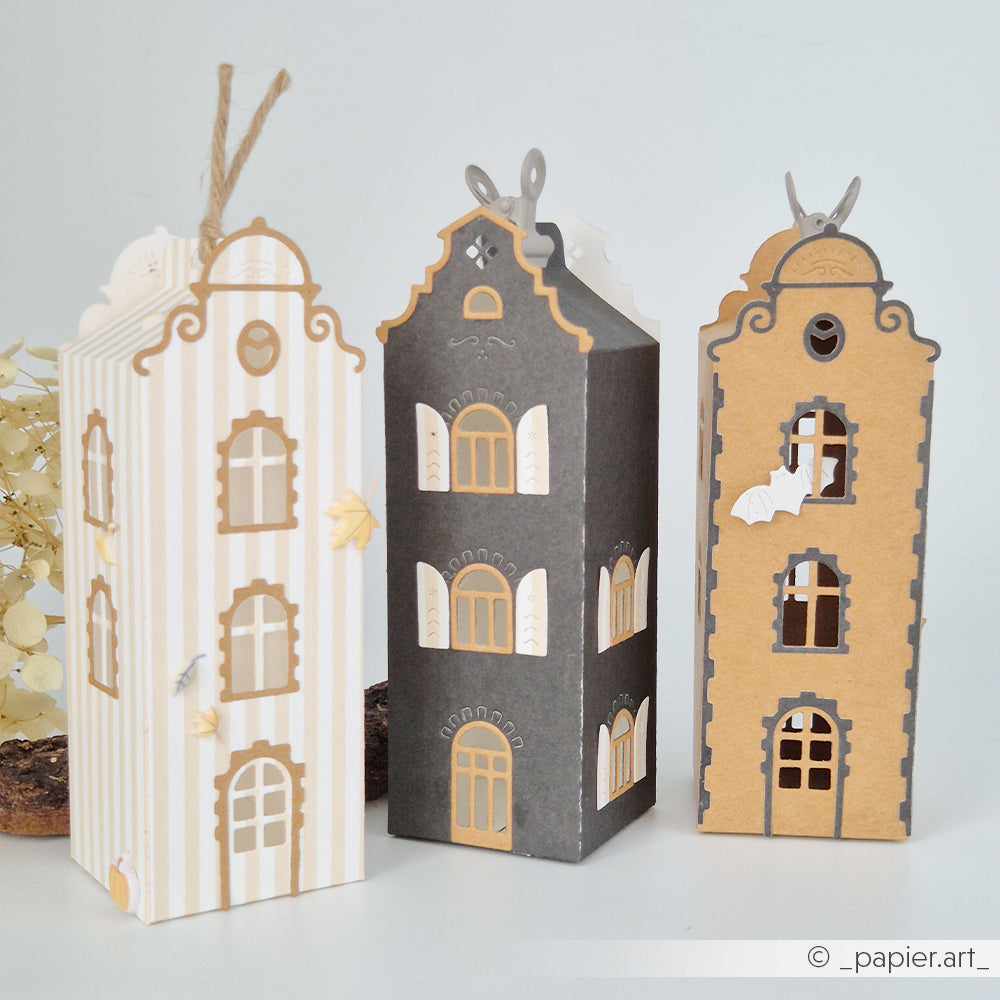 Drei dekorative Papierhäuschen mit filigranen Fenstern und herbstlichen Ausschnitten in Beige, Grau und Hellbraun. Jedes Häuschen ist aus hochwertigem Designpapier gefertigt und mit einer Motivstanze „Häuserbox“ von Stanzsysteme ausgestanzt – für elegante Präzision und einzigartigen saisonalen Charme.