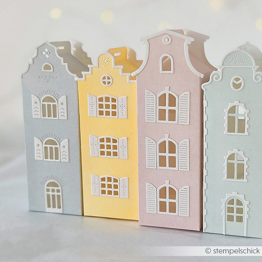 Drei pastellfarbene Papierhäuschen mit detailreichen Fenstern und Türen, nebeneinander auf hellem Hintergrund angeordnet – gefertigt mit der Motivstanze „Häuserbox“ und zarten Designpapieren für filigrane Verzierungen.
