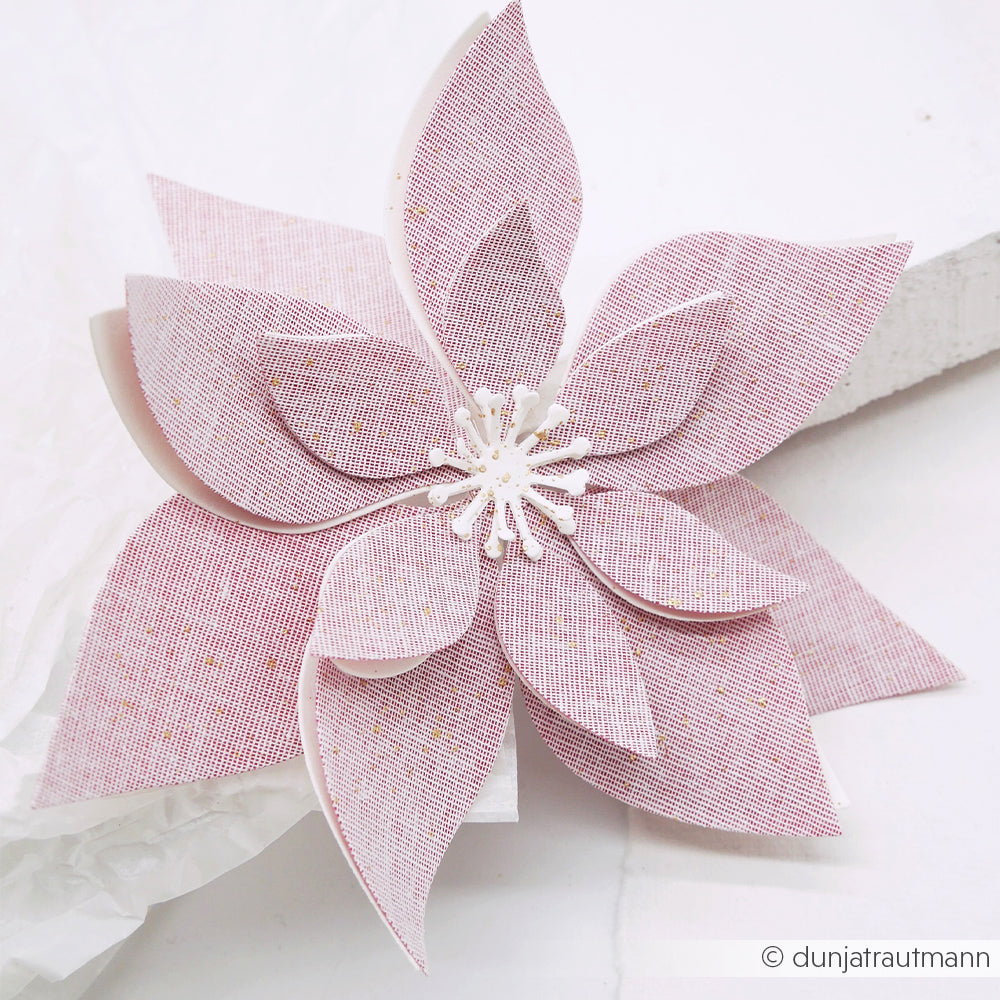 Eine dekorative 3D-Weihnachtsstern-Blume aus strukturiertem Designpapier.
