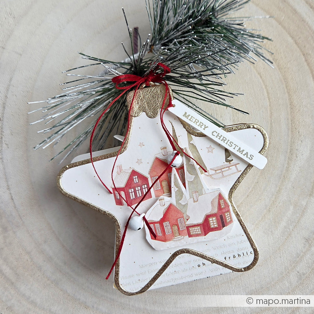 Sternförmiger Weihnachtsschmuck mit einer verschneiten Dorfszene und einem Merry Christmas-Motiv.