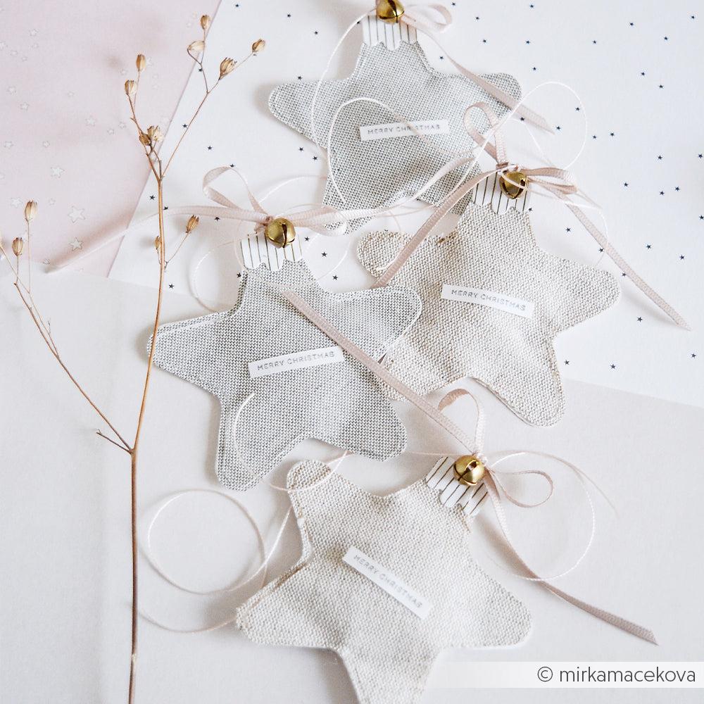 Vier Stern-Anhänger aus Stoff mit der Aufschrift Merry Christmas, verziert mit Bändern, Glöckchen und Stanzmotiven von DieCut Systeme.