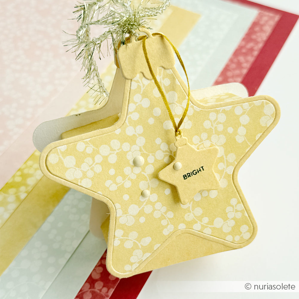 Ein gelbes, sternförmiges Weihnachtskugel-Schmuckstück mit einem Anhänger, auf dem BRIGHT steht.