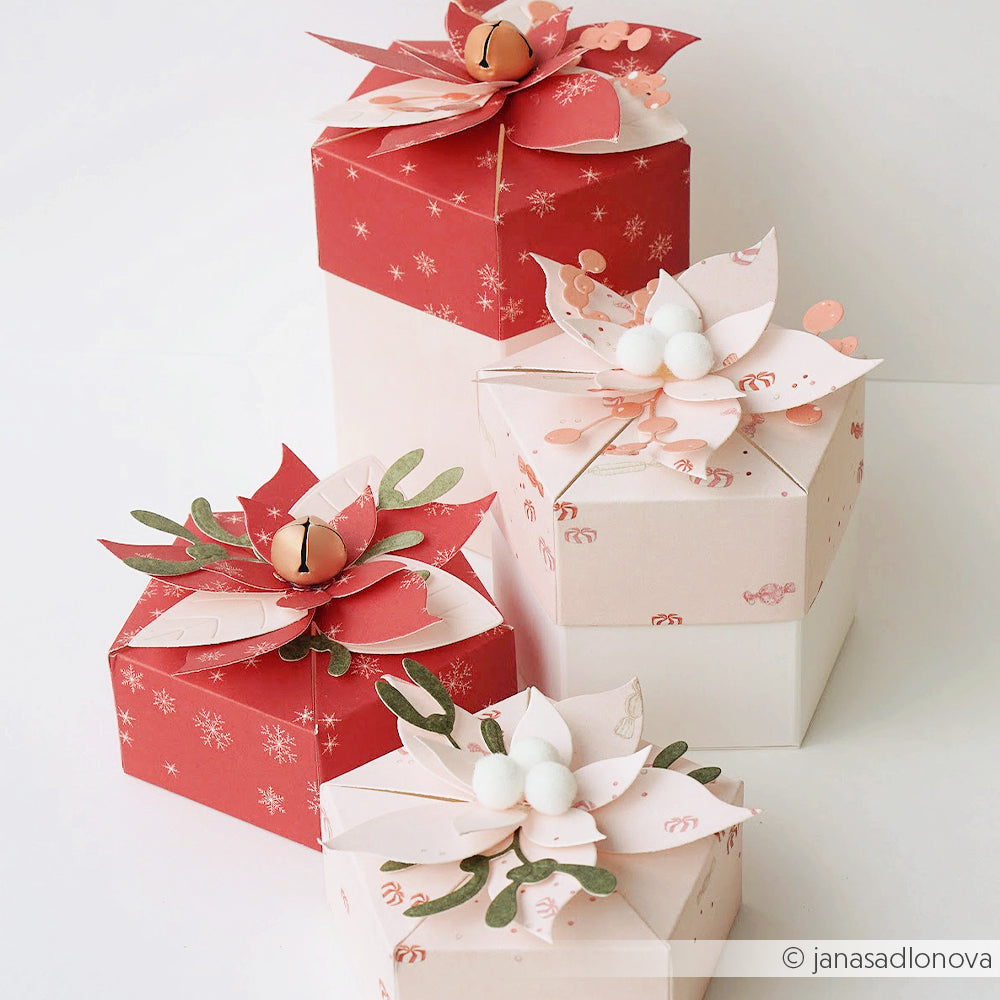 Vier Geschenkboxen in Rot- und Rosatönen, verziert mit einer Motivstanze Weihnachtsstern.