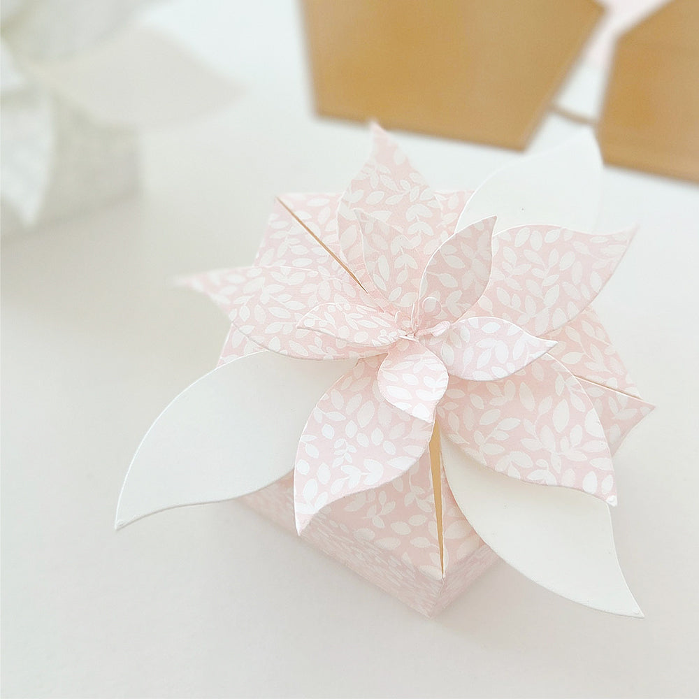 Eine quadratische Geschenkbox mit einer dekorativen Weihnachtsstern-Papierblume.