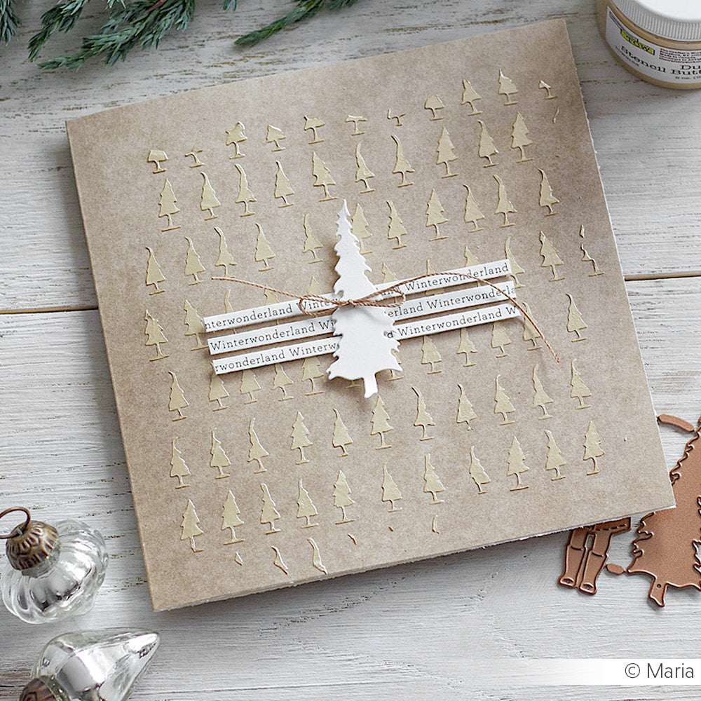 Handgefertigte Winterwonderland-Karte mit kleinen Baumausschnitten, Bindfäden und einem großen Baum in der Mitte, veredelt mit Schablonen und strukturierter Modellierpaste von The Crafters Workshop für zusätzliche Tiefe.