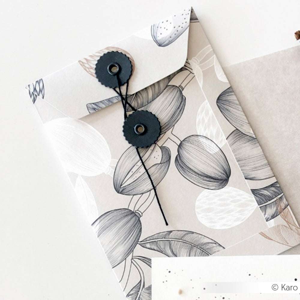 Dekorativer Briefumschlag von Alexandra Renke mit botanischem Motiv, gefertigt aus hochwertigem Designpapier mit Kordelverschluss. Ideal für Liebhaber von Papierprojekten oder Buchbinderei. Platziert auf einer weißen Oberfläche.