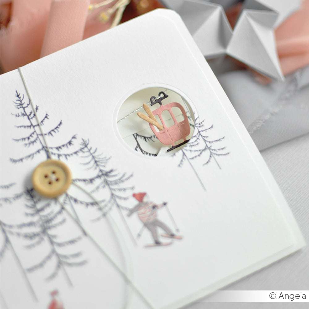 Die weiße Karte von Alexandra Renke aus Designpapier zeigt einen Knopf und einen Skifahrer mit einem kleinen Fenster, das eine rosa Seilbahn zeigt.