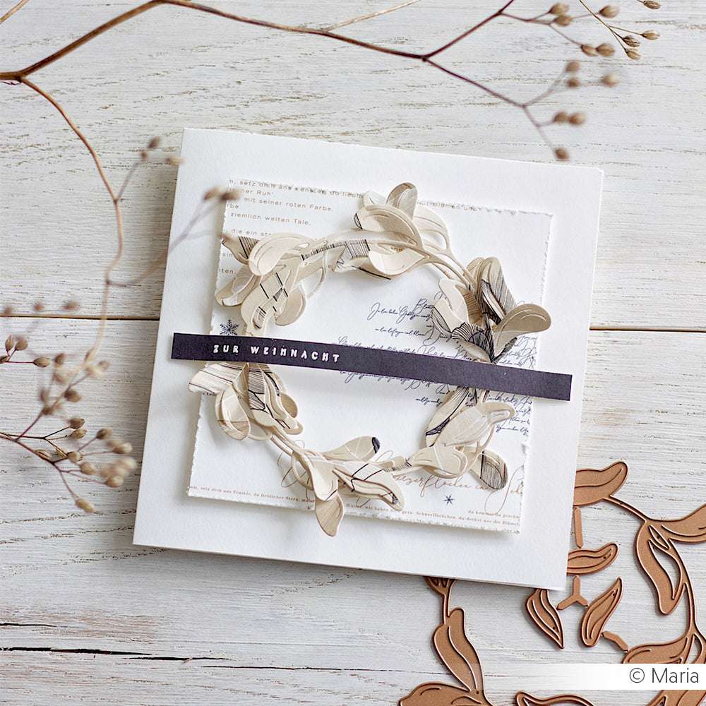 Handgefertigte Weihnachtskarte von Alexandra Renke mit neutralem Kranz aus Motivstanze und "FUR WEIHNACHT" auf der Vorderseite, ausgestellt auf einer Holzfläche.