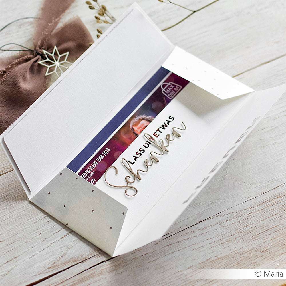 Weißer Umschlag mit Karte innen, teilweise geöffnet auf einer hellen Holzunterlage mit Band und Trockenblumen - ideal zum Ausstellen von Alexandra Renke Stanzformen oder zur Verwendung von DieCut Systemen für einzigartige, personalisierte Kreationen.