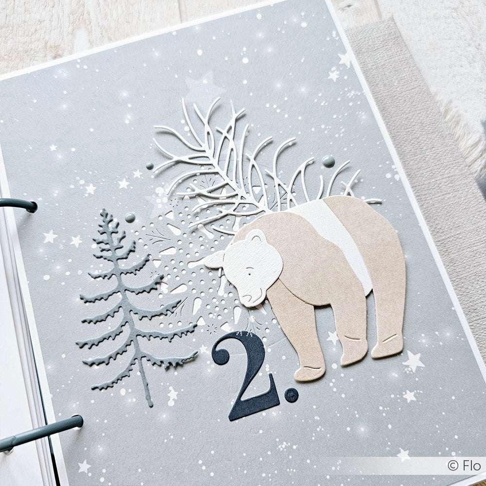 Eine winterliche Scrapbook-Seite von Alexandra Renke mit einer großen Papiercollage aus Bär, Baum und Nummer 2, die mit Designpapieren gestaltet und mit einer Motivstanze veredelt wurde.
