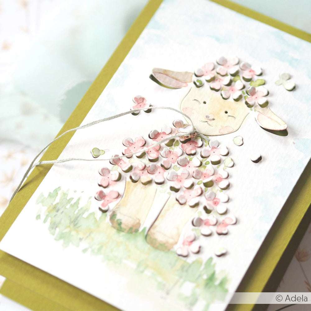 Handgemachte Karte von Alexandra Renke mit einem niedlichen Lamm und rosa und weißen 3D-Blumen, die mit der Motivstanze detailreich gestaltet wurden, auf einem leuchtend grünen Hintergrund.