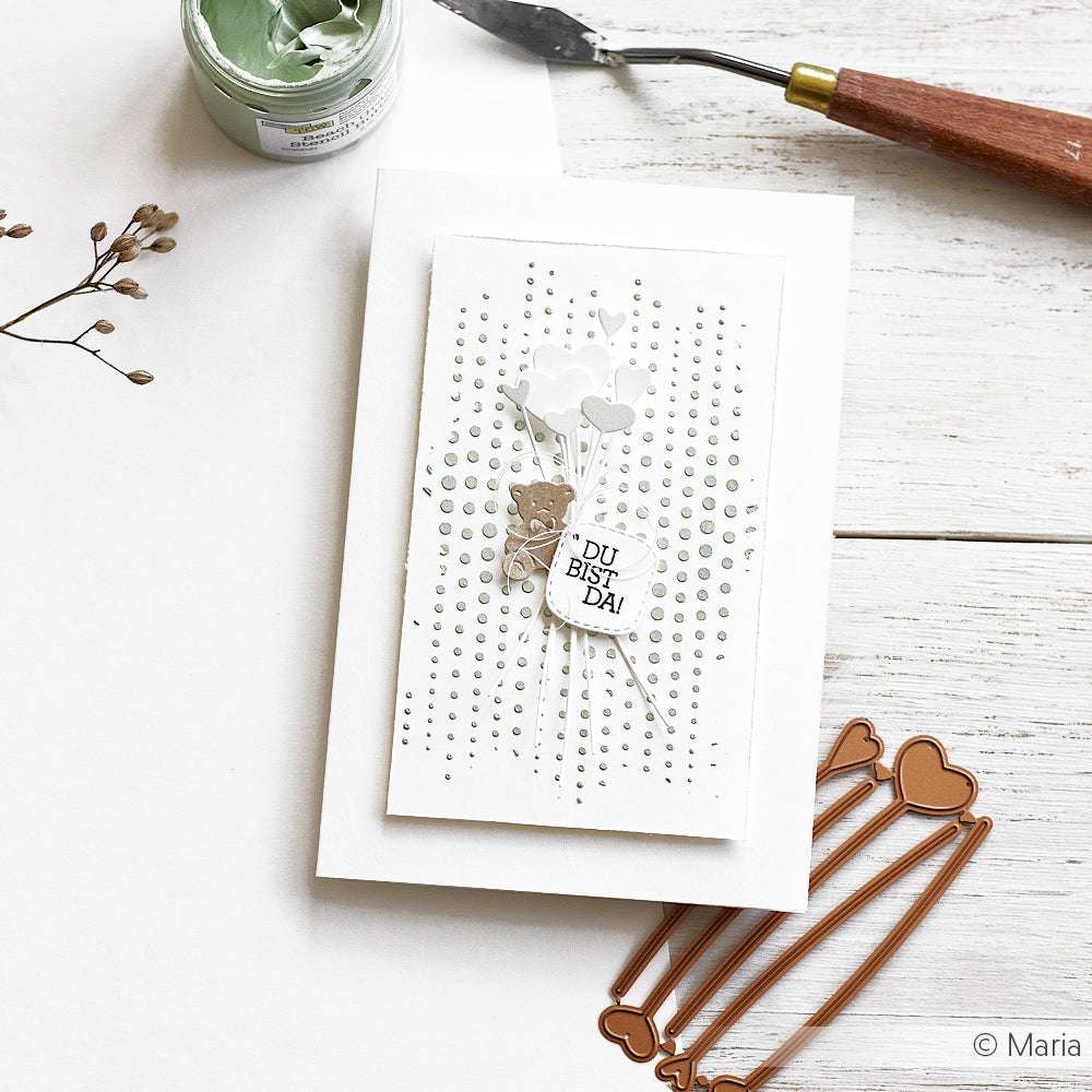 Handgemachte Karte mit Herzluftballons und "Du bist da!"-Text, umgeben von Bastelwerkzeugen - perfekt, um mit The Crafters Workshop Schablonen oder Stencil Butter Textur und Dimension hinzuzufügen.