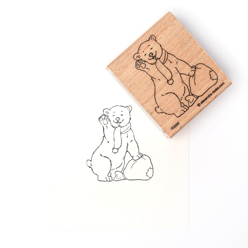 Ein Alexandra Renke Holzstempel zeigt Eisbärbaby Kaja, den winkenden Bären neben seinem gestempelten Stempelgummi-Bild auf weißem Papier.